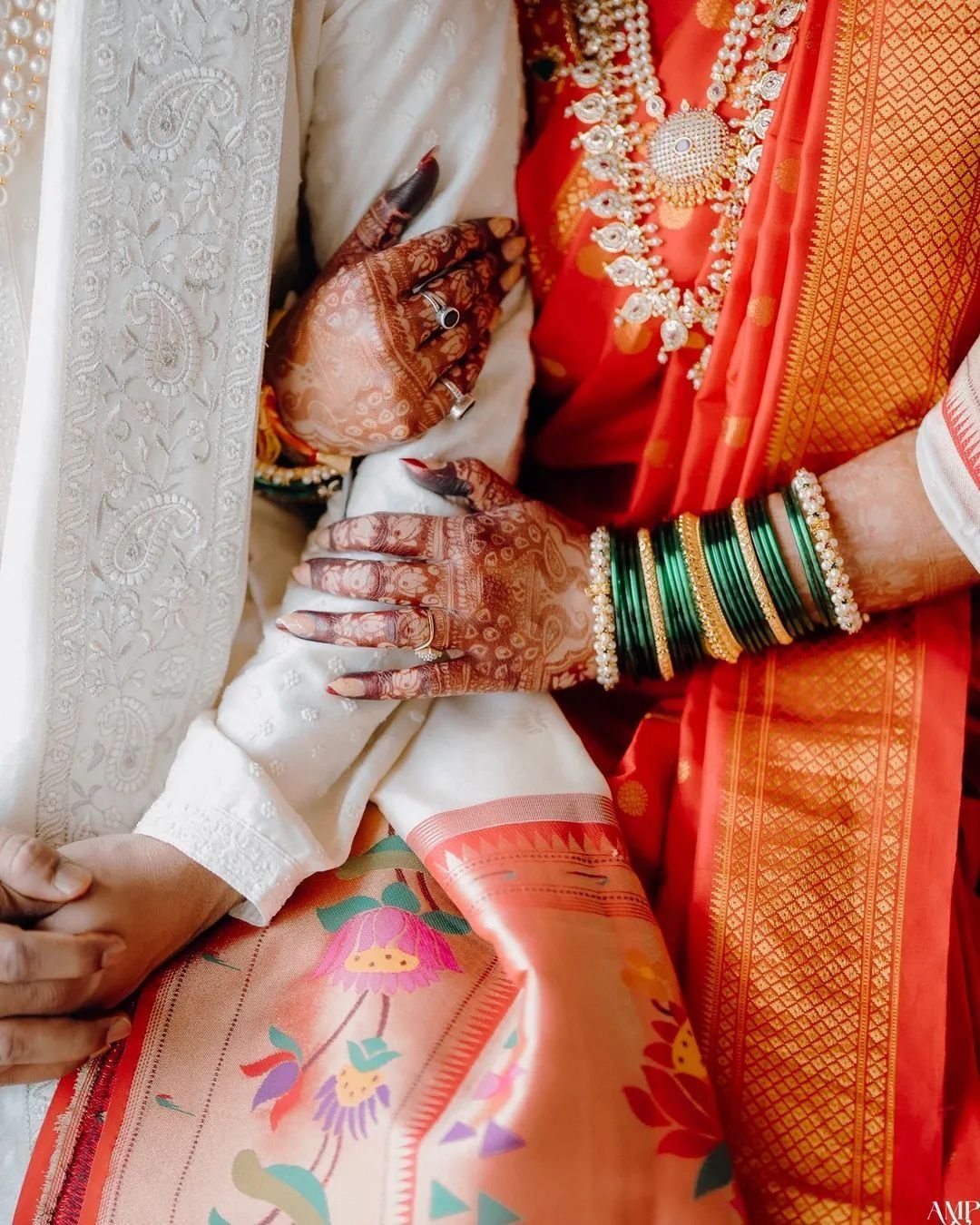 Bride's mehndi-covered hands resting on the groom's arm in traditional dress