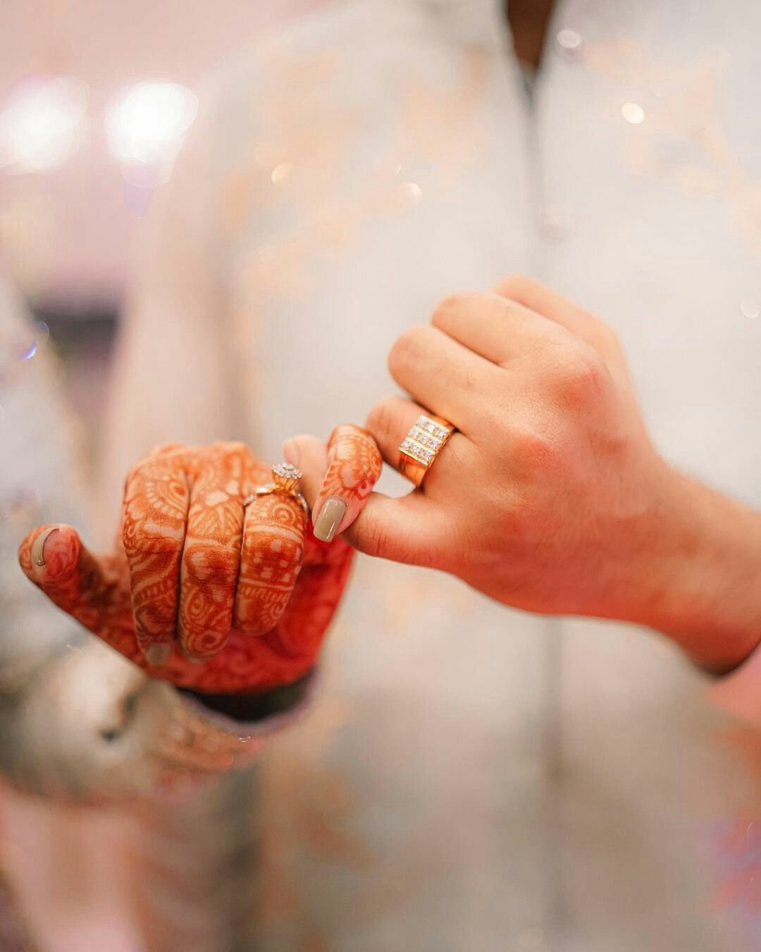 Close-up of the couple's hands with engagement rings and bridal mehndi