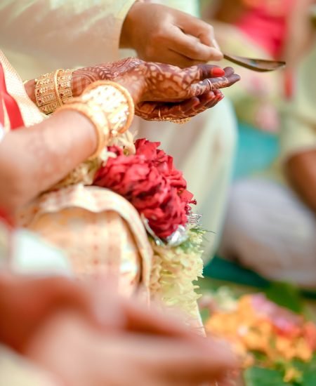 A vertical closeup of a Hindu bride's henna-adorned hands during a traditional wedding ceremony